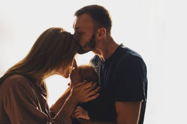 Mutlu genç ebeveynler ve oğulları birbirlerini öpüyor.