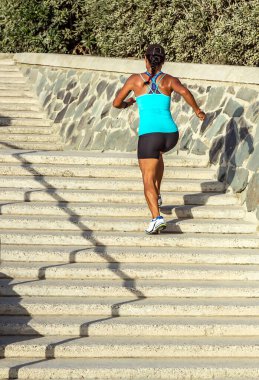 Kadın koşucu merdivenlerden yukarı tırmanıyor.