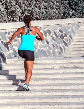 Spor kadın koşucusu yaz günü şehir sokaklarında koşuyor.