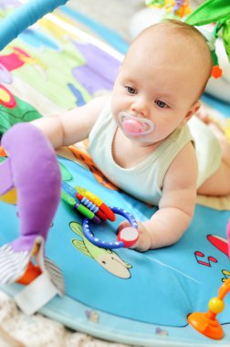 sweet baby playing toys on the rug clipart