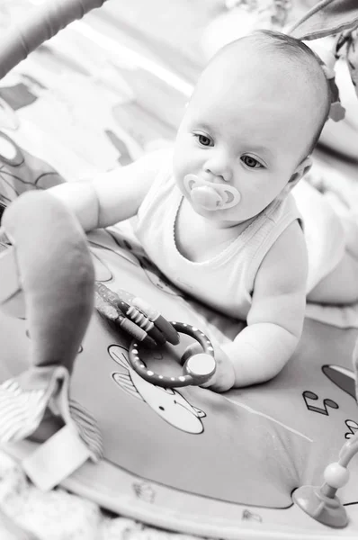 かわいい赤ちゃんが遊ぶおもちゃも敷物の上 — ストック写真