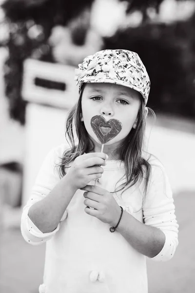 Cute Little Girl Eating Heart Shaped Lollipop Outdoors Summer — Stock Photo, Image