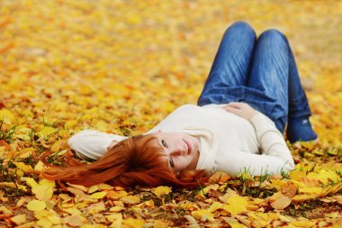Kızıl saçlı kız sonbahar çayır üzerinde yatıyor