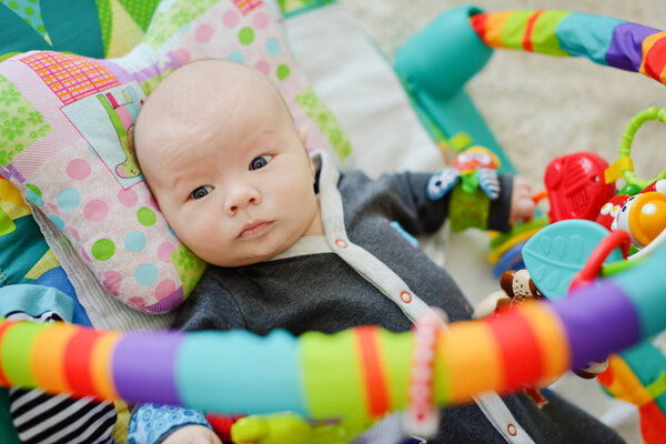 baby on the toy rug on orthopedic pillow