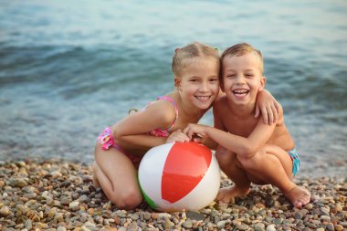 erkek ve kız kardeş plajda top oynuyor
