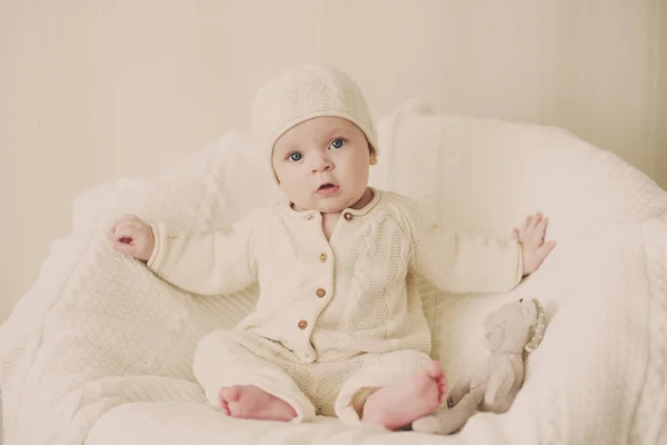 かわいい赤ちゃんニット スーツを着ては肘掛け椅子に座っています — ストック写真