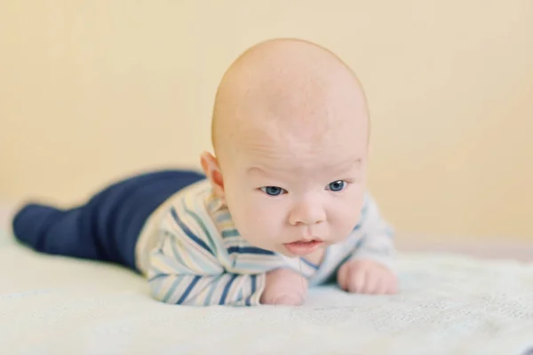 生まれたばかりの赤ちゃんをベッドの上に彼の頭を維持しようとしています — ストック写真