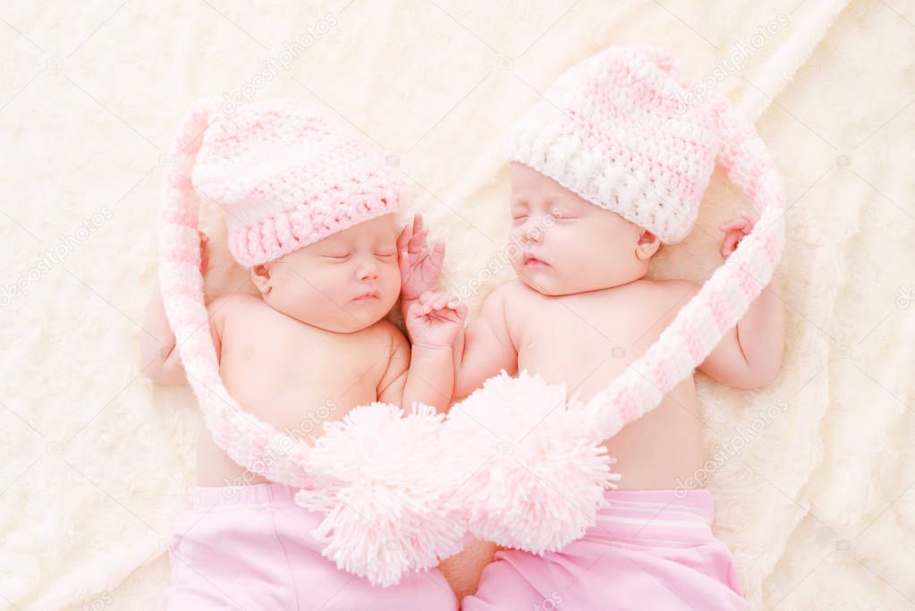 sleeping twins wearing funny hats with big pompoms