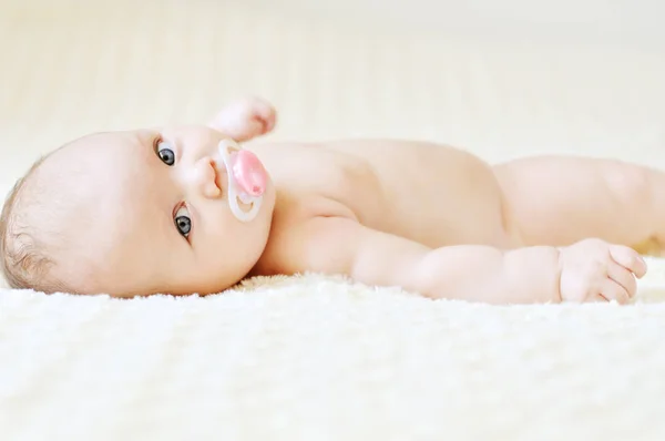 ベッドの上のおしゃぶりを持つ幸せな赤ちゃん — ストック写真