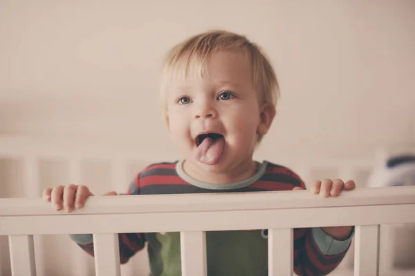 Drôle Bébé Debout Dans Lit Montrant Langue — Photo