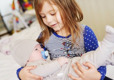 Kız kardeşi yeni doğan erkek kardeşini evde tutuyor.