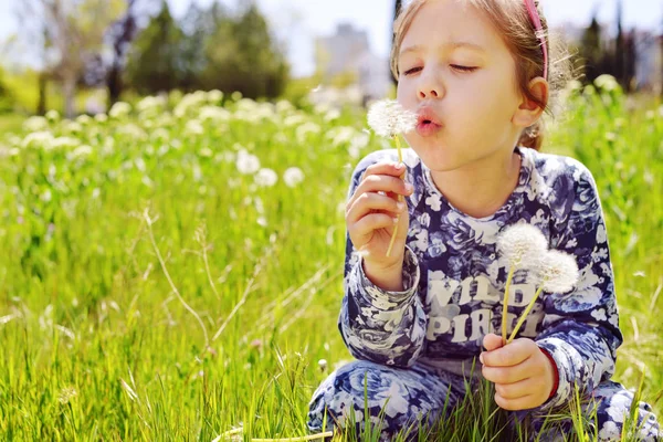 屋外にタンポポの花を吹いて幸せな子供女の子 — ストック写真