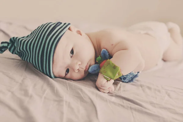 Baby Mit Armbandspielzeug Auf Händen Die Auf Dem Bett Liegen — Stockfoto