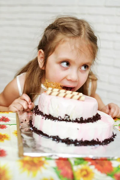 Menina mordendo bolo de aniversário — Fotografia de Stock