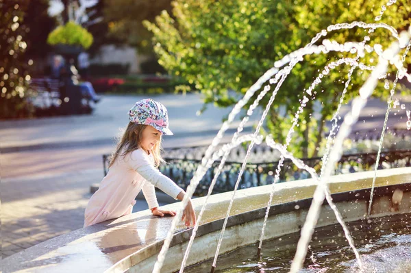 Mädchen spielt mit Brunnenwasser — Stockfoto