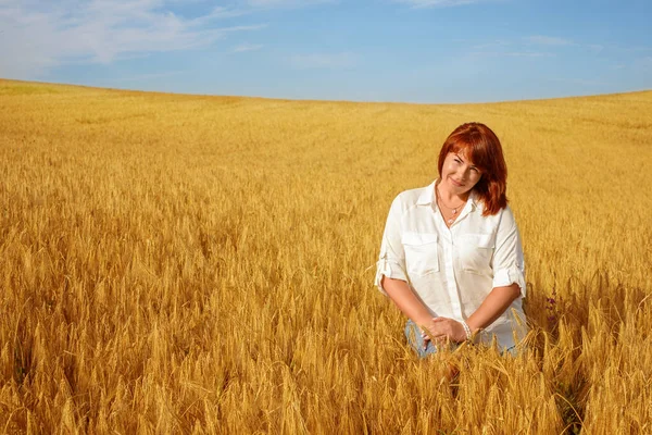 幸せな赤毛の女性が小麦畑に座って — ストック写真