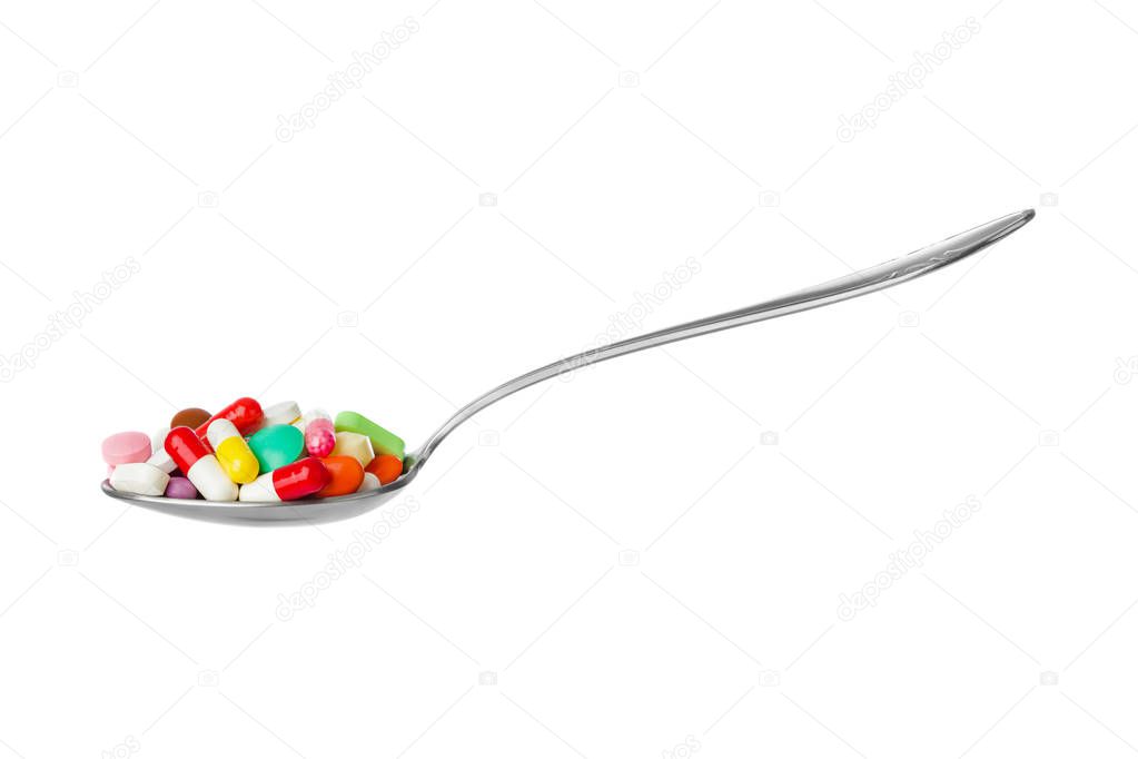 Spoon with pills isolated on white background