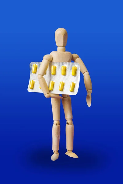 Figurine jouet en bois avec des pilules sur bleu — Photo