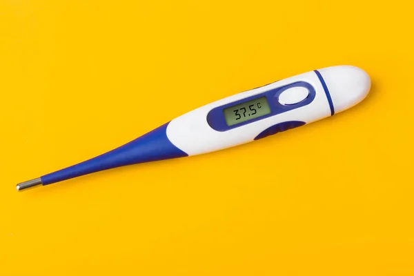 Elektronik tıbbi termometre (37.5 derece) sarı arkaplanda izole. — Stok fotoğraf