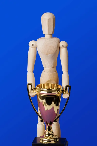 Holzspielzeugfigur mit goldenem Pokal auf blauem Grund — Stockfoto