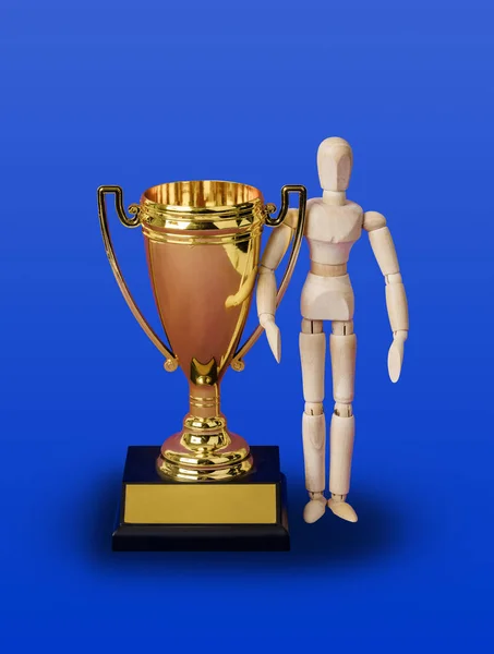 Wooden toy figure and golden trophy cup on blue — ストック写真