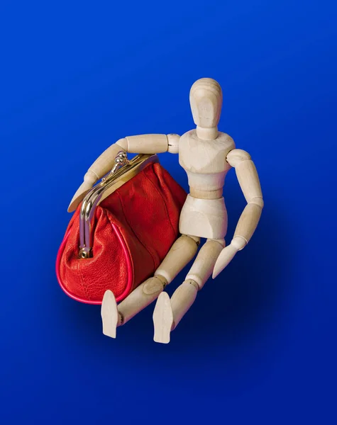 Wooden toy figure with red purse on blue — ストック写真