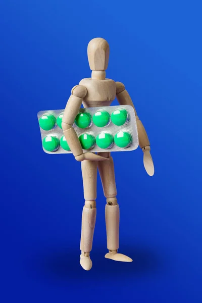 Wooden toy figure with pills on blue — Stock Photo, Image