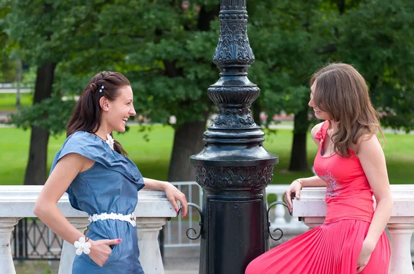 Portrait of two beautiful young girlfriends in park and talking with happy smiles — Stock Photo, Image