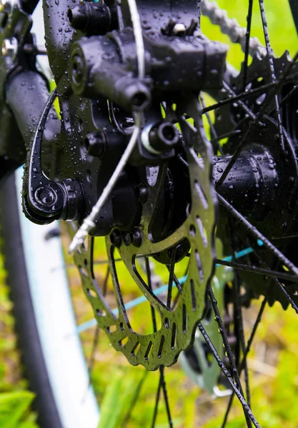 Wet after rain a bicycle brake disc on green grass background.