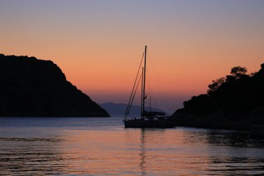 Gün batımında yelkenli yat ada yakınlarında demirledi