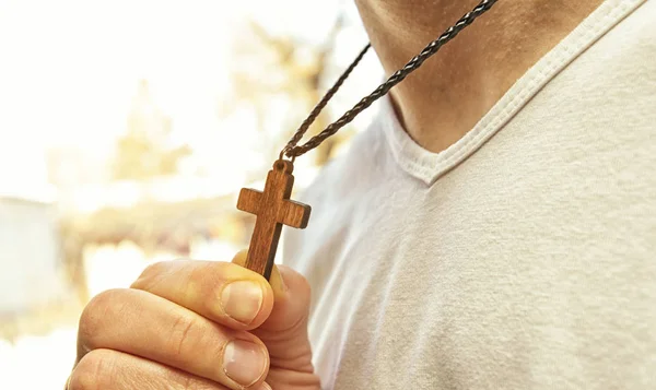The wooden cross necklace on man\'s neck