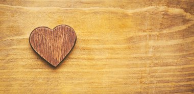 Ahşap masa üzerinde küçük bir ahşap kalp. Ve senin metin için büyük bir yer. Sevgililer kavramı