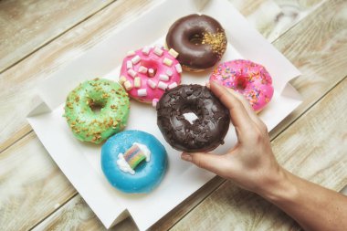 Kadın eli bir çörek kutusu ahşap masa üzerinde farklı çörek ile yukarıda tutan