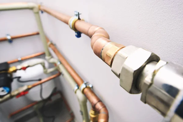 Different copper and plastic pipes and other valves in the boiler room