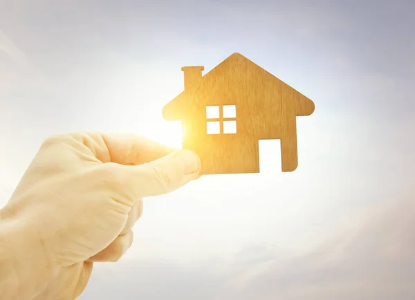 Die Hand Des Mannes Hält Ein Flaches Holzhaus Gegen Die — Stockfoto