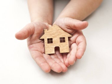 Küçük bir çocuk ahşap düz ev beyaz zemin üzerine onun elinde tutan