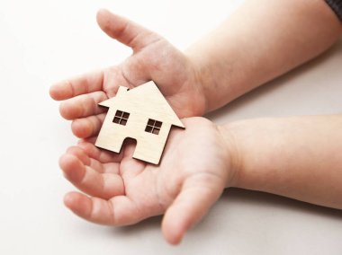 Küçük bir çocuk ahşap düz ev beyaz zemin üzerine onun elinde tutan