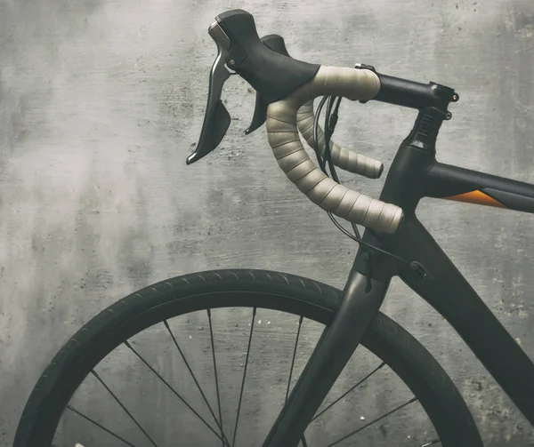 A black race bike in front of metal gray wall