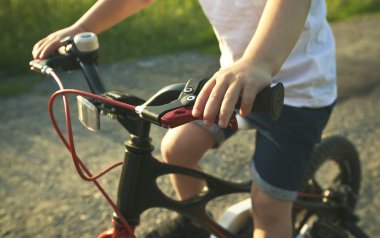 Küçük çocuk asfalt yolda bisiklete biniyor.