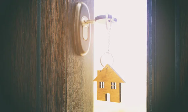 Uma bugiganga em forma de casa na chave no buraco da fechadura — Fotografia de Stock