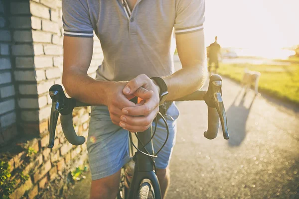 El joven con bicicleta está caminando por la carretera. — Foto de Stock