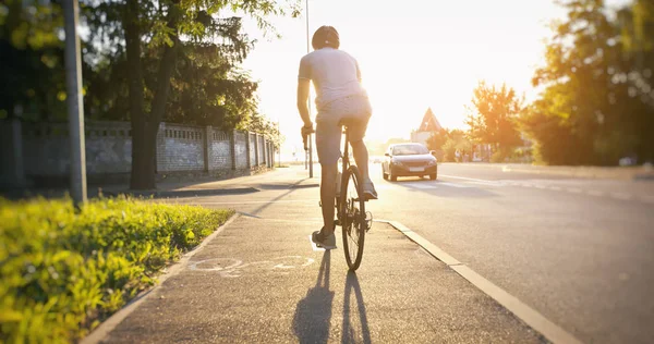 The young guy is riding the bike by roads in the city — Stock Photo, Image