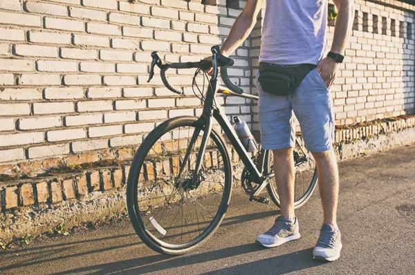 O jovem com bicicleta está caminhando pela estrada — Fotografia de Stock