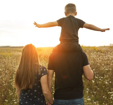 Oğul babanın omuzlarında oturuyor ve onlar bakıyorlar.