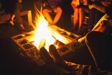 Arkadaş grubu gece şenlik ateşi yakınında oturuyorlar.