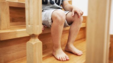 Evde ahşap merdivenlerde oturan çocuk 