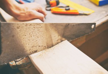 Adam tahta tahtayı testereyle kesiyor.