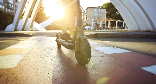 A jovem está montando na scooter elétrico através do ev — Fotografia de Stock