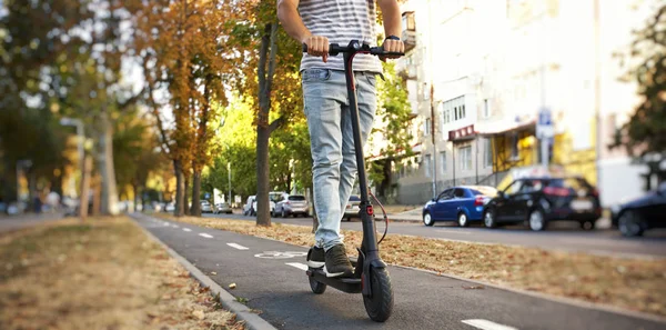 El joven está montando en el scooter eléctrico a través de la incluso — Foto de Stock