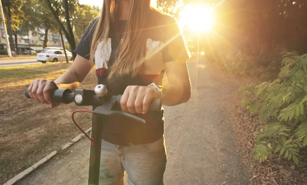 A jovem está montando na scooter elétrico através do ev — Fotografia de Stock